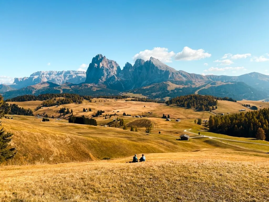 Deux personnes assises contemplant l'alpage et pics emblématiques des Dolomites