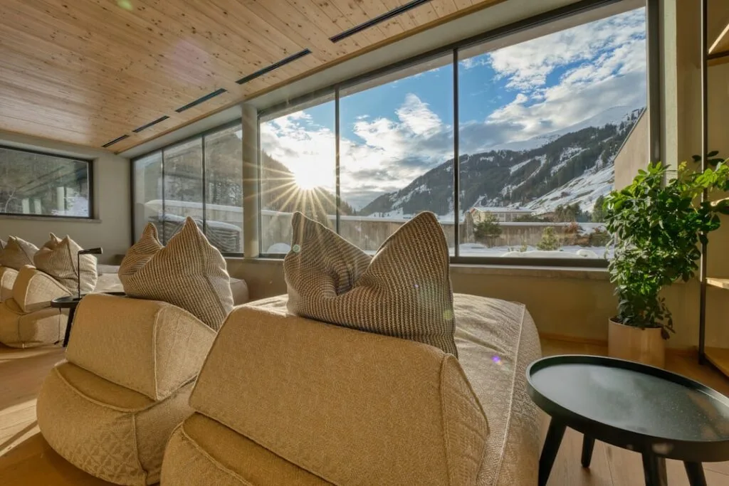 Salon d'hôtel avec larges baies donnant sur les montagnes des Dolomites