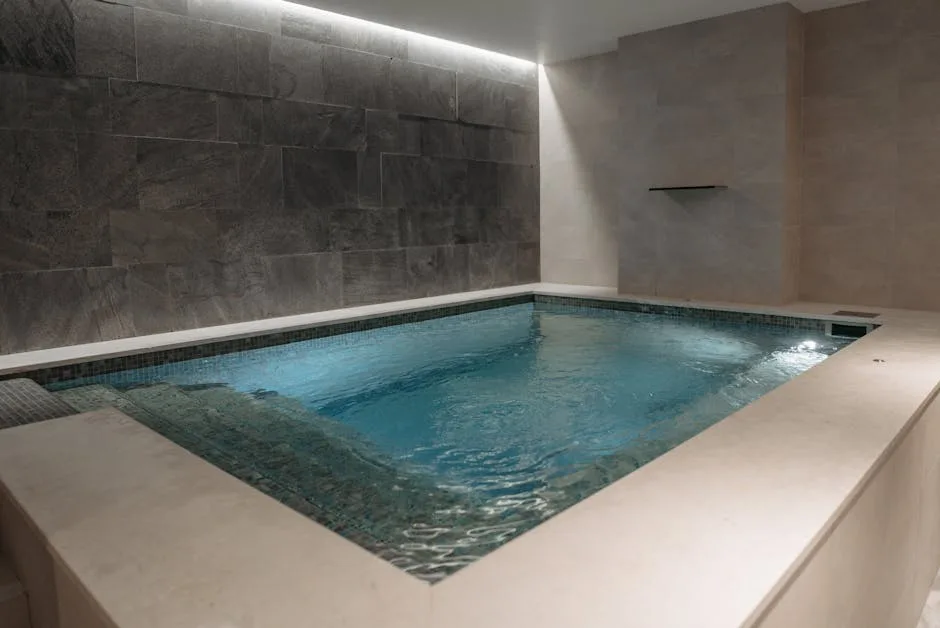Piscine intérieure du spa hôtelier aux Dolomites, carrelage gris et eau bleue