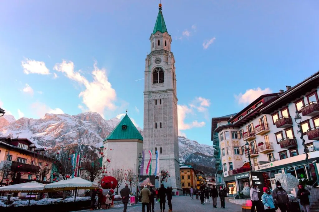 Campanile de Cortina d'Ampezzo devant les Dolomites enneigées, place animée