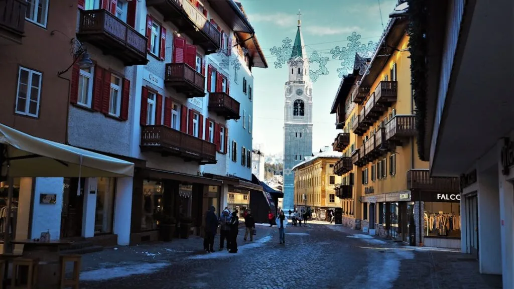 Rue piétonne bordée de boutiques et clocher dans les Dolomites