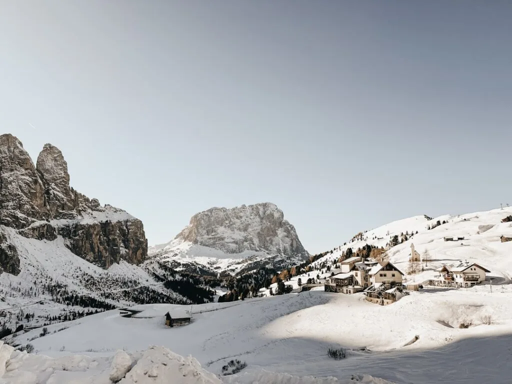 Village enneigé perché sous un massif imposant des Dolomites