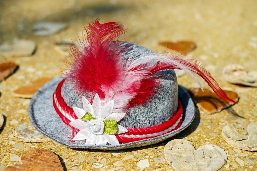 Chapeau tyrolien gris orné de plumes rouges, posé sur le sol des Dolomites