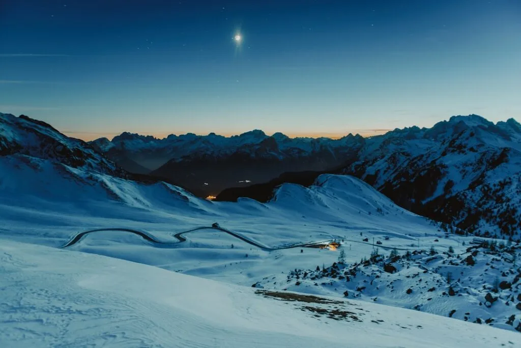 Route enneigée et virages des Dolomites au crépuscule lunaire