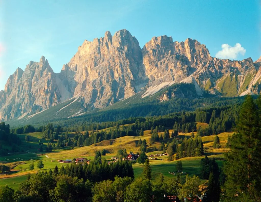Village alpin niché dans les prairies devant les sommets des Dolomites