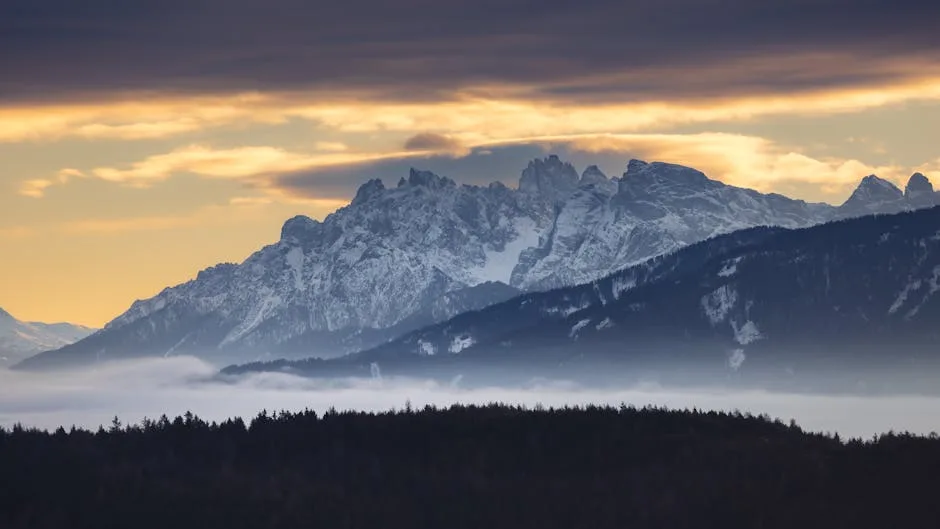 Chaîne enneigée des Dolomites surplombant brume matinale et forêt
