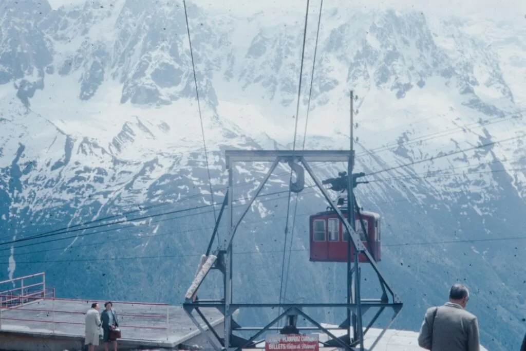 Téléphérique rouge au sommet, câbles devant massifs enneigés des Dolomites