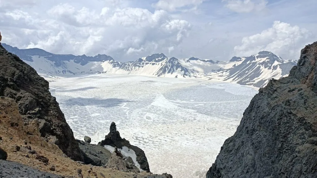 Vaste plateau glaciaire blanc encadré par falaises et sommets enneigés