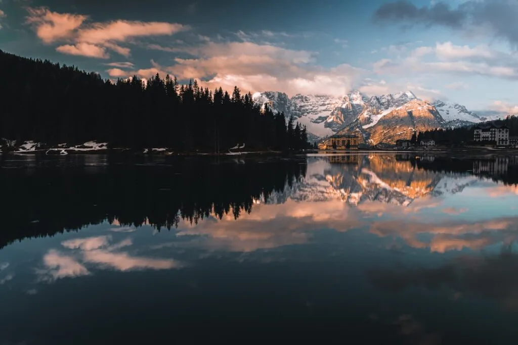 Lac calme reflétant les sommets enneigés des Dolomites au coucher
