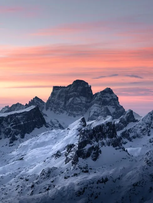 Massif enneigé des Dolomites au lever, ciel rose et violet.