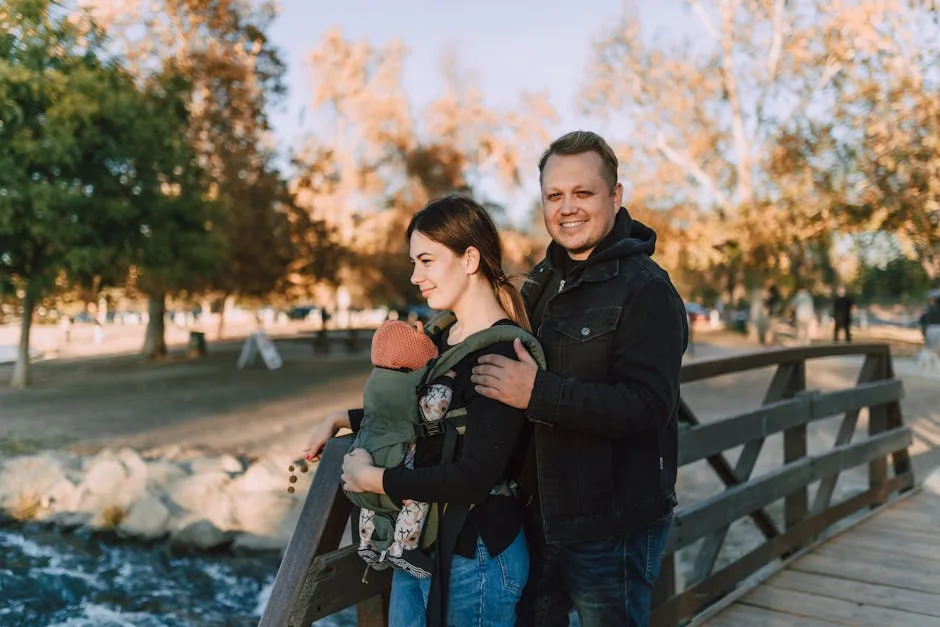 Parents souriants emmenant bébé en porte-bébé sur un pont en bois