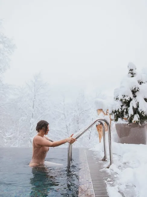 Personne entrant dans une piscine extérieure entourée de neige aux Dolomites