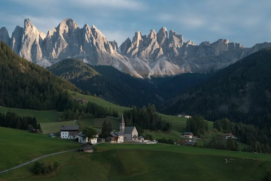 Petit village alpin avec église devant les aiguilles des Dolomites.