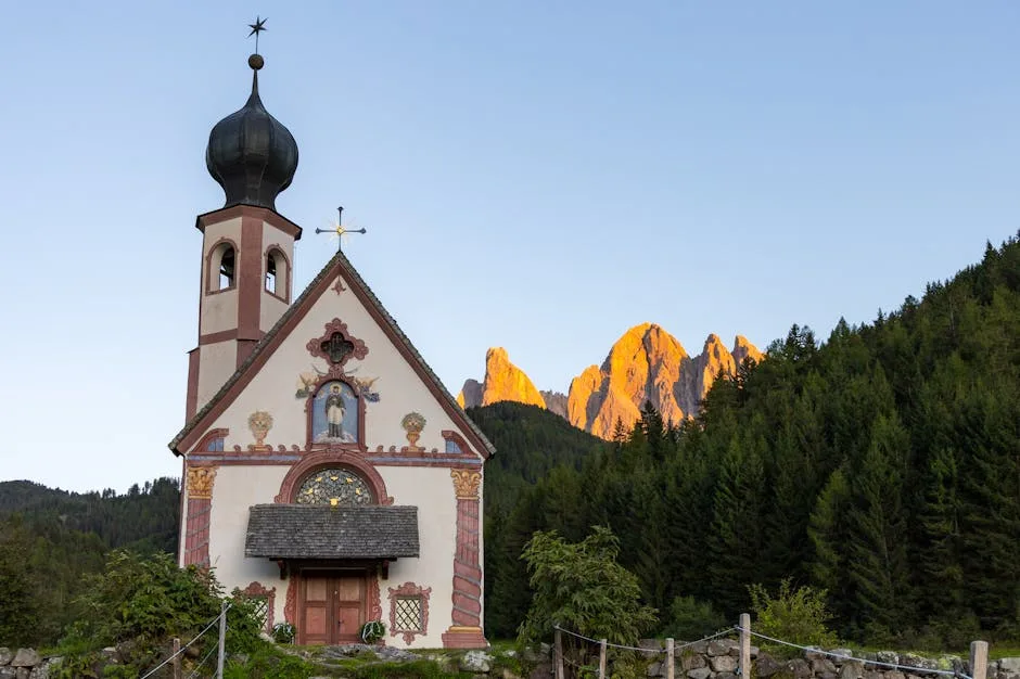 Chapelle baroque devant la forêt et les sommets des Dolomites dorés