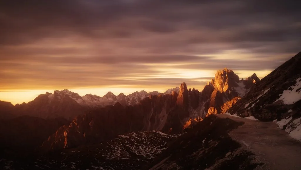 Sentier enneigé au coucher de soleil face aux crêtes des Dolomites
