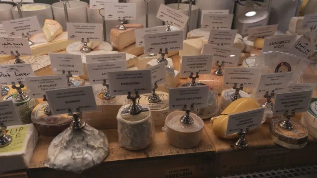 Vitrine de fromages variés étiquetés sur un présentoir en bois