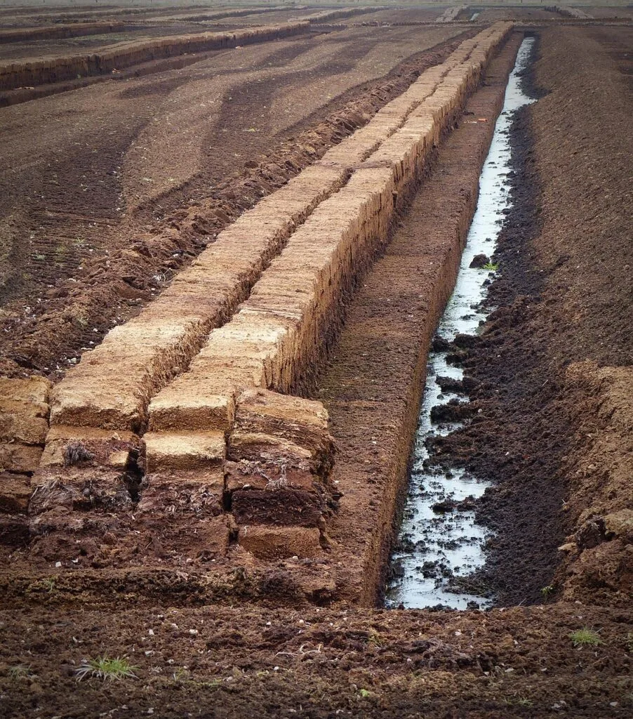 Blocs de tourbe empilés le long d'un fossé de drainage