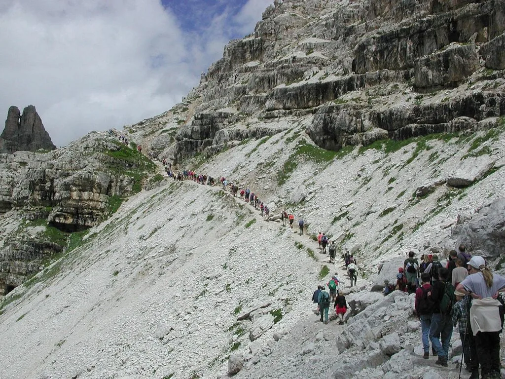 Randonneurs en file sur sentier rocheux des Dolomites