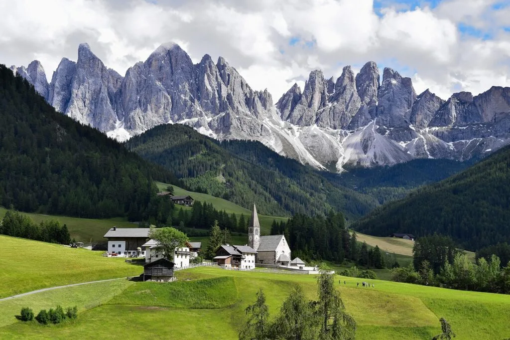 Hameau tranquille avec église et aiguilles rocheuses des Dolomites en arrière-plan