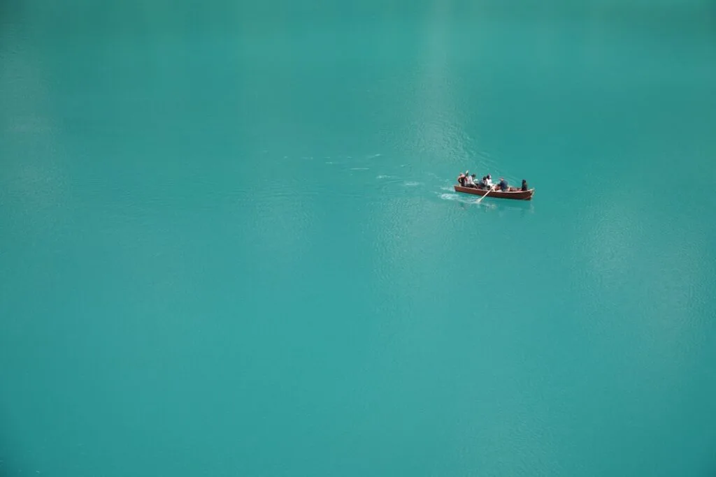 Barque à rame avec plusieurs personnes sur lac turquoise des Dolomites