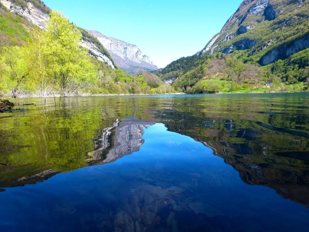 Lac alpin aux eaux calmes reflétant falaises et forêts des Dolomites