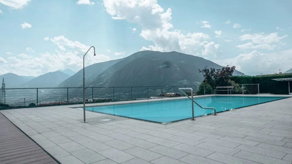 Piscine extérieure d'hôtel sur terrasse, vue sur vallée et Dolomites