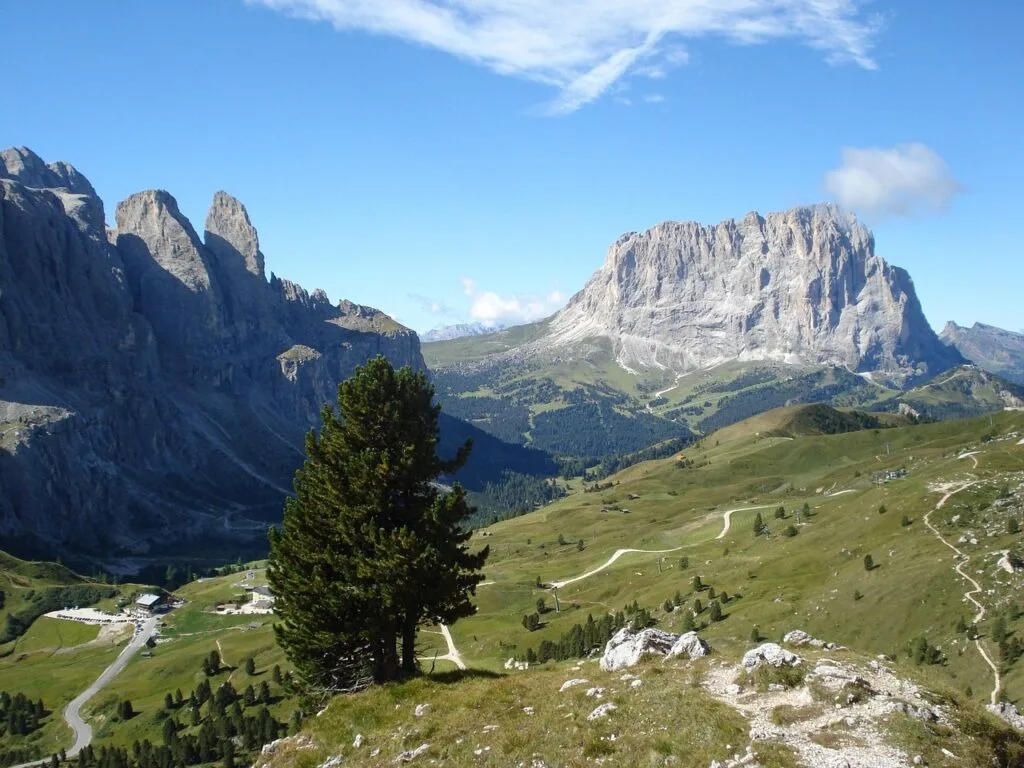 Vallée verte des Dolomites avec route sinueuse et grand rocher