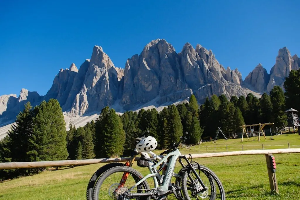 Vélos appuyés sur barrière devant les aiguilles des Dolomites
