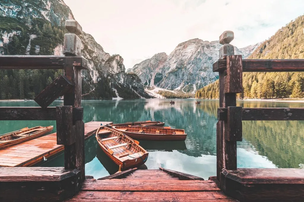 Barques en bois amarrées sur un lac émeraude entouré des Dolomites