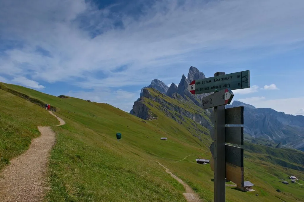Panneau de randonnée indiquant sentiers sur alpages avec crêtes des Dolomites