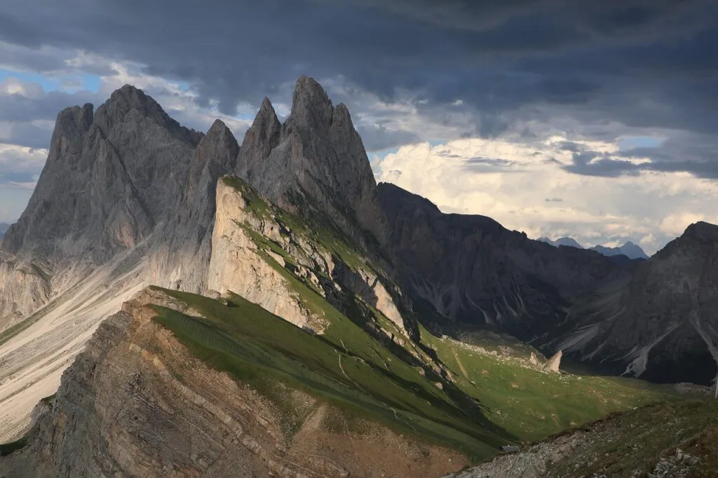 Dents acérées et crêtes herbeuses des Dolomites sous ciel orageux