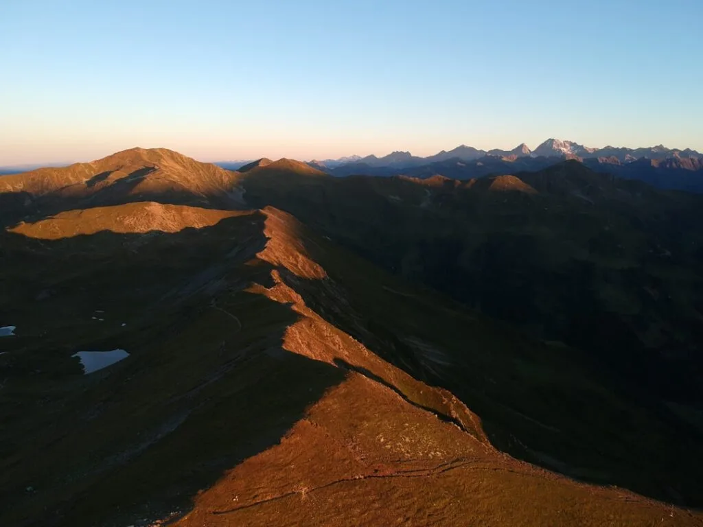Crête herbeuse éclairée par l'aube sur les hauteurs des Dolomites