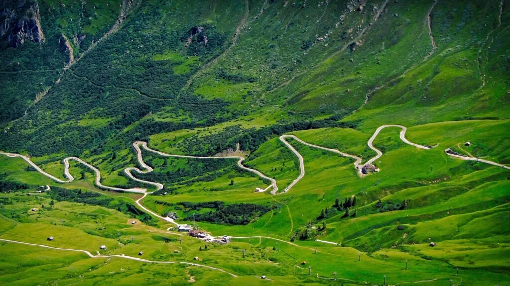 Route en lacets serpentant prairies verdoyantes au cœur des Dolomites