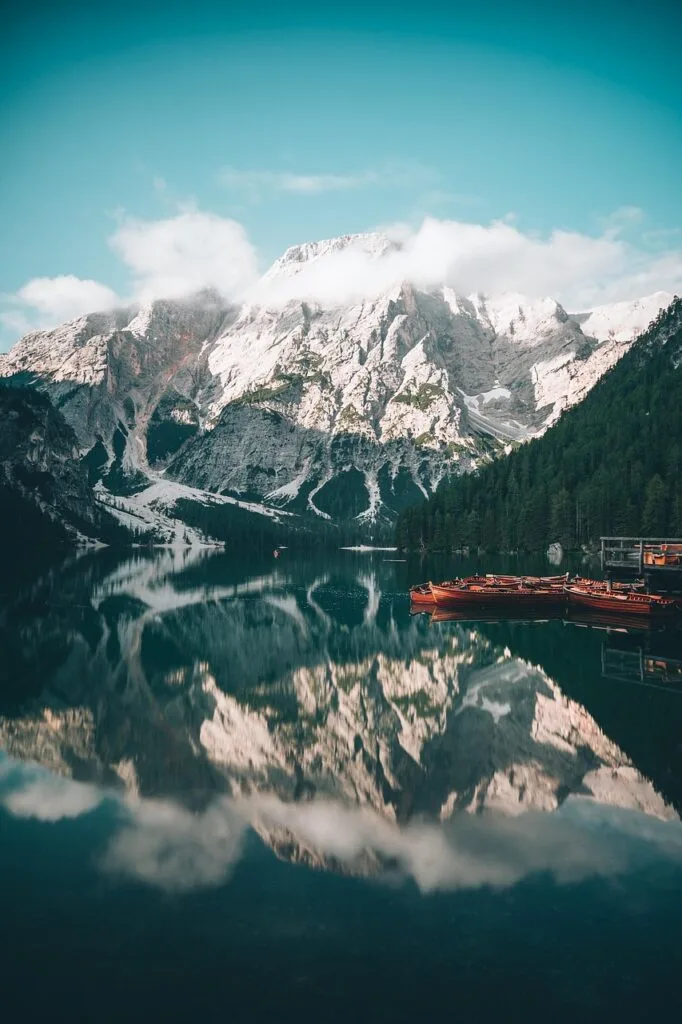 Lac miroir reflétant les sommets des Dolomites, barques amarrées