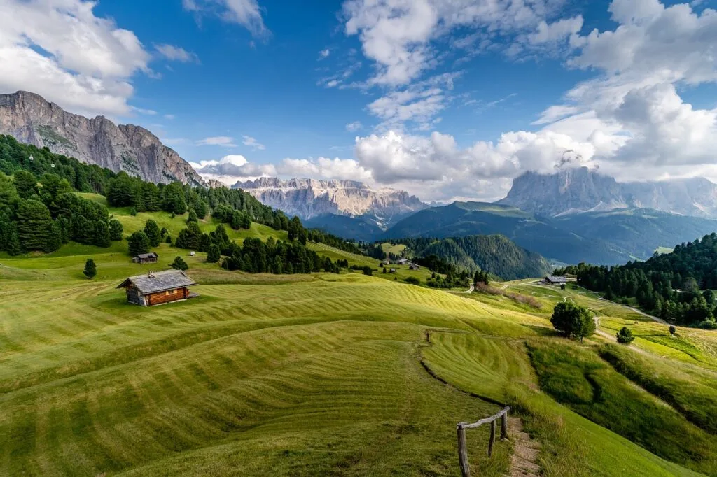 Alpages ondulants avec chalet solitaire et vues sur les Dolomites