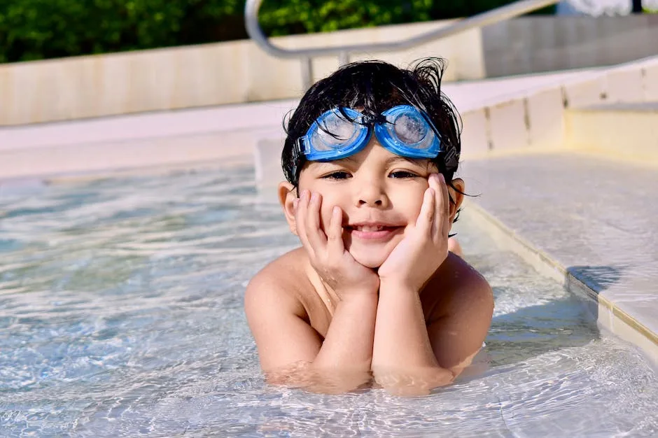 Enfant souriant avec lunettes de natation dans piscine du spa familial aux Dolomites