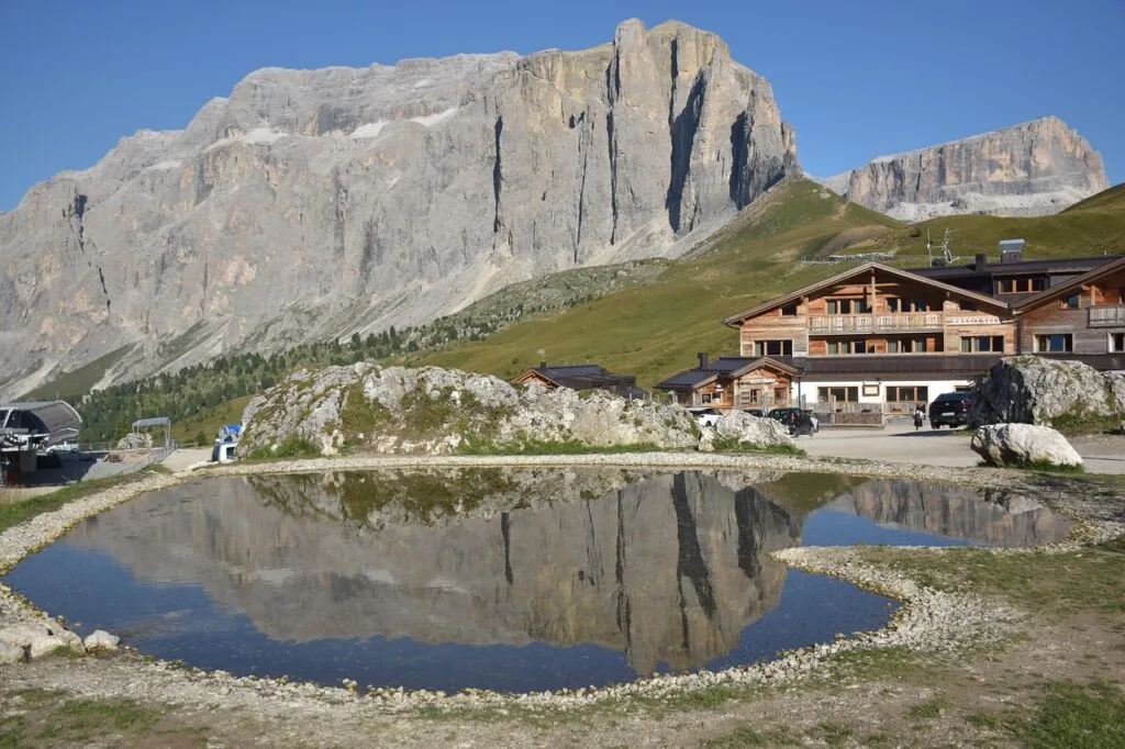 Refuge en bois au pied d'une falaise, reflet dans un bassin, Dolomites.