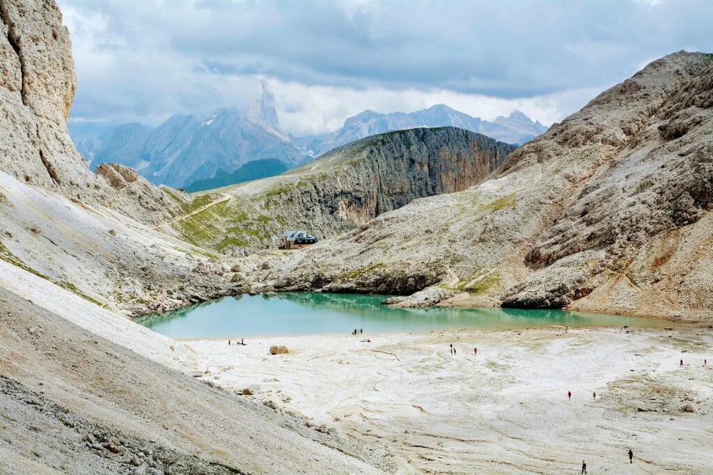 Lac turquoise entouré de roches calcaires et refuge lointain, Dolomites